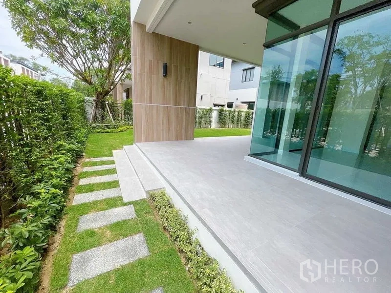Detached House for sale in Don Mueang, Bangkok - Covered outdoor terrace with stepping-stone path and hedge-lined garden.