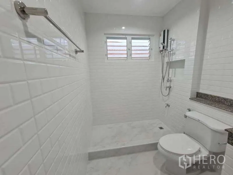 Detached House for rent in Suan Luang, Bangkok - White tiled bathroom with walk-in shower, window and modern sanitary ware.