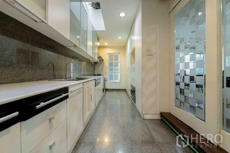 สำนักงานที่บ้าน ให้เช่าในBang Rak, Bangkok - ครัวสไตล์แกลลียาว เคาน์เตอร์หิน ตู้เก็บของสีขาว เตาแก๊ส และประตูกระจก