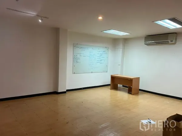 Office Space for rent in Khlong Toei, Bangkok - Meeting space with a wall-mounted whiteboard, bright overhead lighting, laminate flooring and an air-conditioning unit.