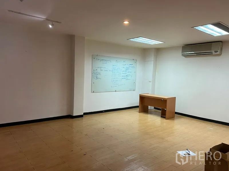 Office Space for rent in Khlong Toei, Bangkok - Meeting space with a wall-mounted whiteboard, bright overhead lighting, laminate flooring and an air-conditioning unit.