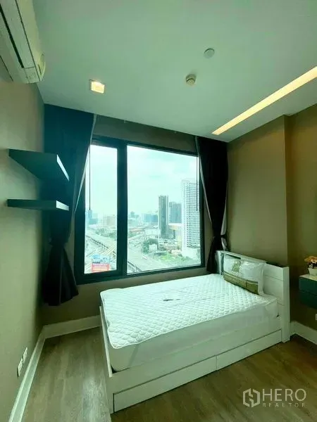 คอนโด ให้เช่าในBangkok - ห้องนอนสว่างพร้อมหน้าต่างบานใหญ่ เตียงนอน พื้นไม้ และวิวเมืองกว้างไกล