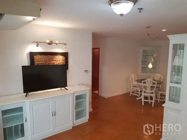 Condominium for rent or sale in Watthana, Bangkok - TV console and storage cabinet facing a cozy dining nook with round table and accent lighting.