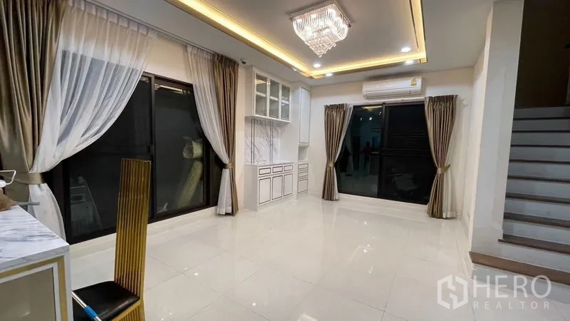 Detached House for rent or sale in Prawet, Bangkok - Spacious living area with large sliding windows, built-in cabinets and recessed ceiling lights.