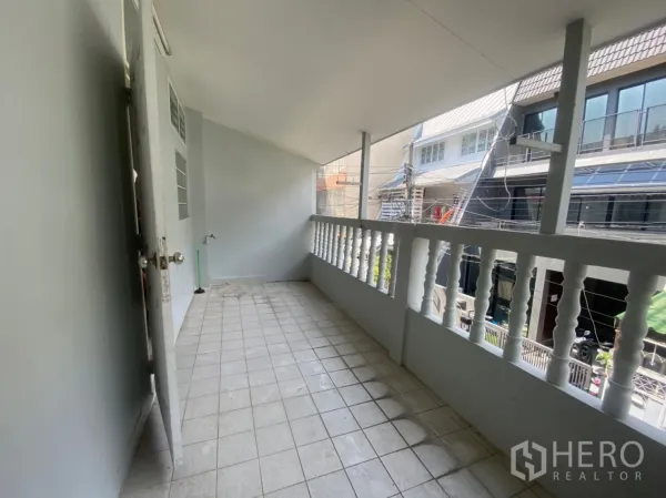 联排别墅 出租在Watthana, Bangkok - 楼上走廊式阳台，白色栏杆，可见邻里街景