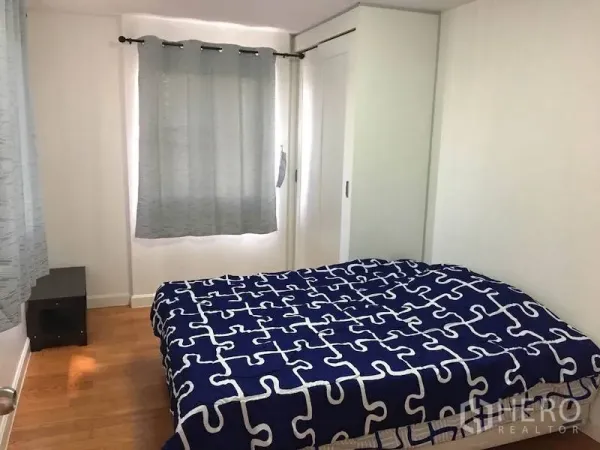 Condominium for rent or sale in Yan Nawa, Bangkok - Bright bedroom with blue patterned duvet, wood floor, grey curtains, and sliding wardrobe in a Bangkok condo.