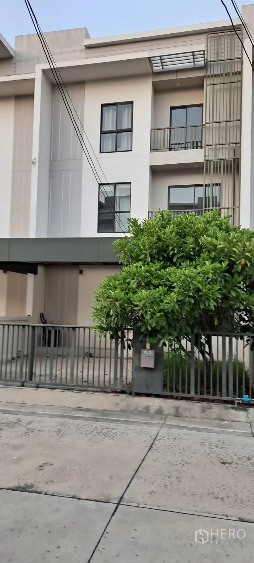 Townhouse for rent in Saphan Sung, Bangkok - Modern three-storey townhouse exterior with gated driveway, covered carport and balconies.