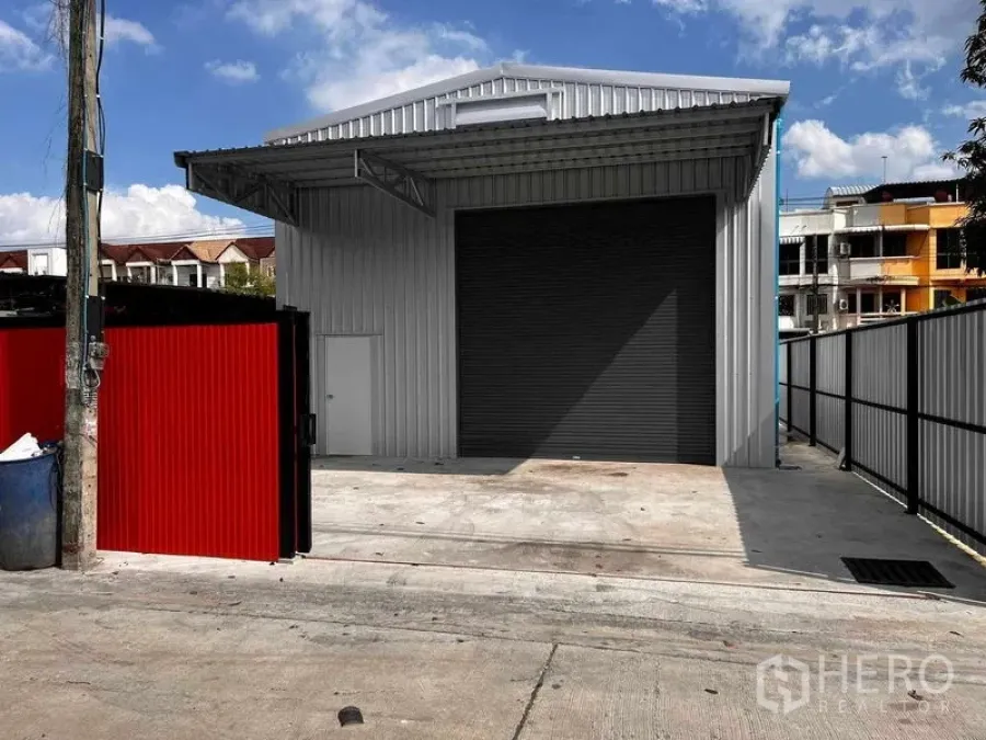 货栈 出租在Lat Phrao, Bangkok - 曼谷拉抛现代独栋金属外墙仓库，配大卷闸门、围栏大门与混凝土装卸区。