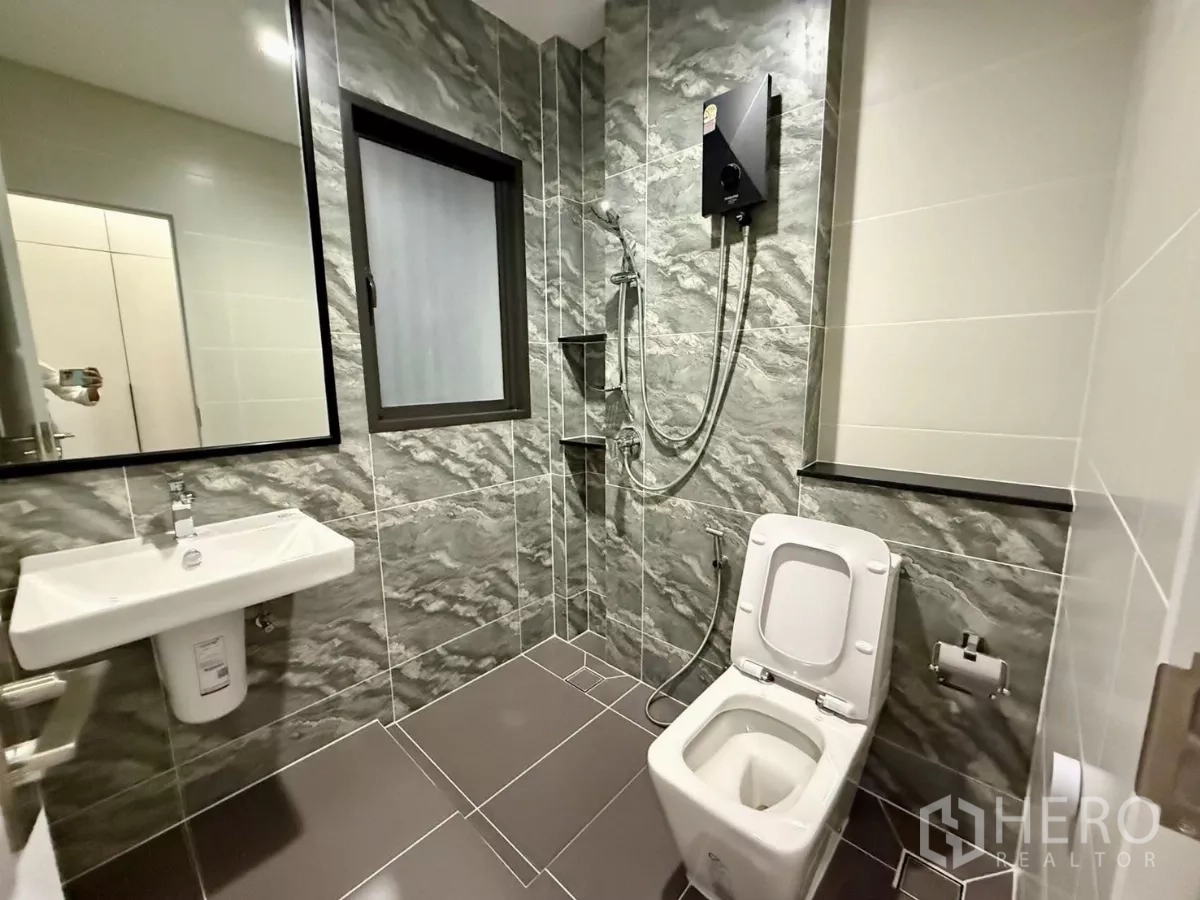 Detached House for rent in Bang Phli, Samut Prakan - Bathroom with grey marble wall tiles, shower set and window.