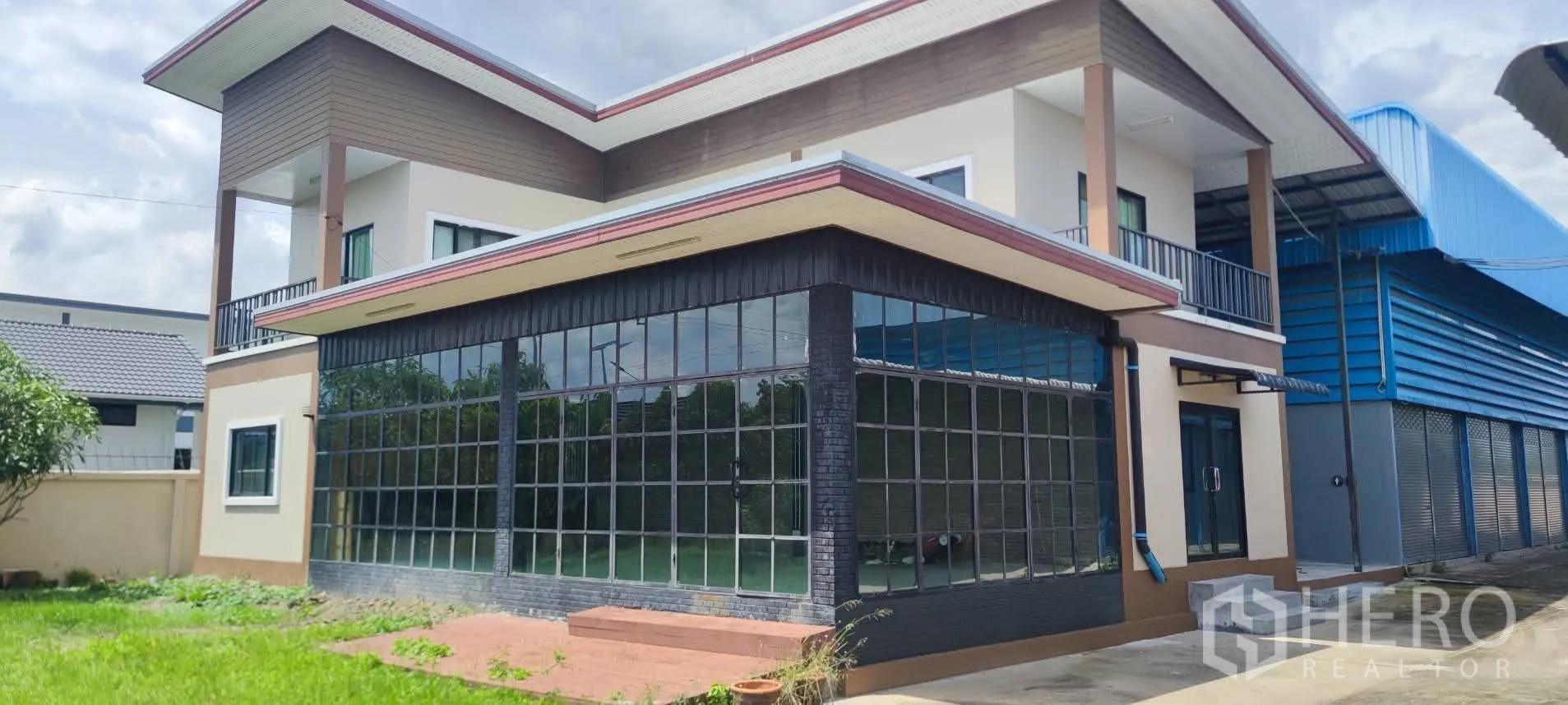 Warehouse for sale in Thung Khru, Bangkok - Corner of modern office with full-height windows beside blue warehouse.