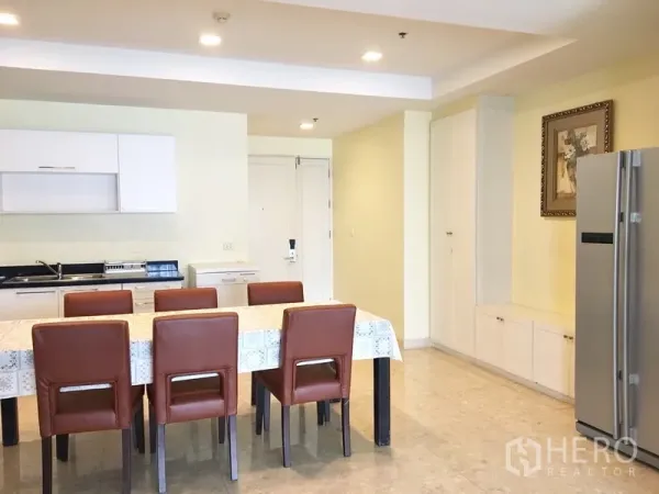 Condominium for rent in Khlong Toei, Bangkok - Open-plan dining and kitchenette with six-seat table, white cabinets, and stainless refrigerator.