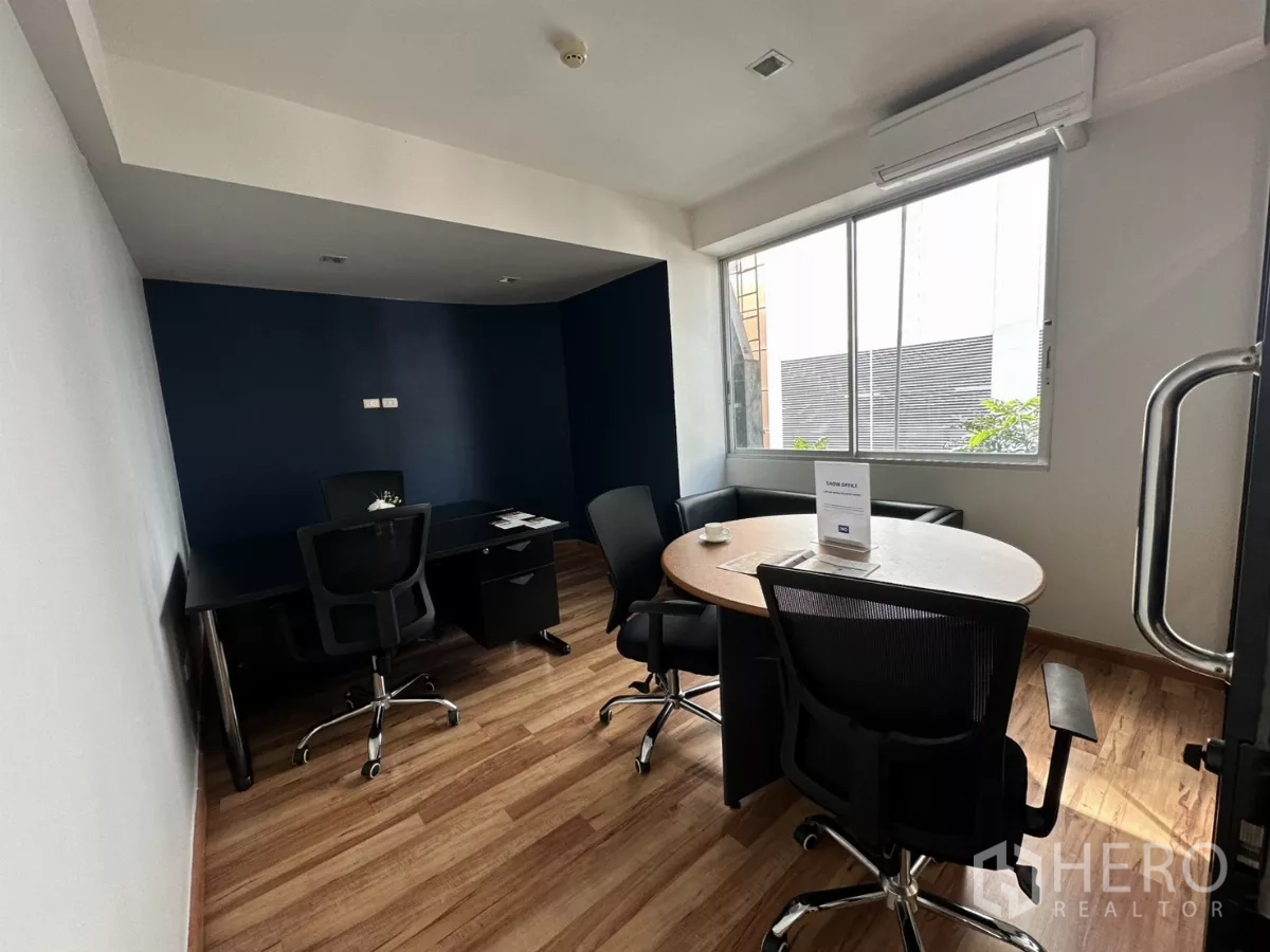 办公空间 出租在Watthana, Bangkok - 私密办公室，圆形会议桌、深蓝强调墙与采光窗。
