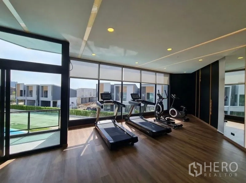 Townhouse for rent in Bang Phli, Samut Prakan - Resident fitness room with treadmills and exercise bike overlooking the townhouse community.