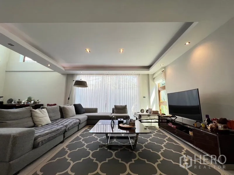 独立式住宅 出售在Chatuchak, Bangkok - 采光充足的家庭起居室，落地窗与纱帘，组合沙发与影音柜。