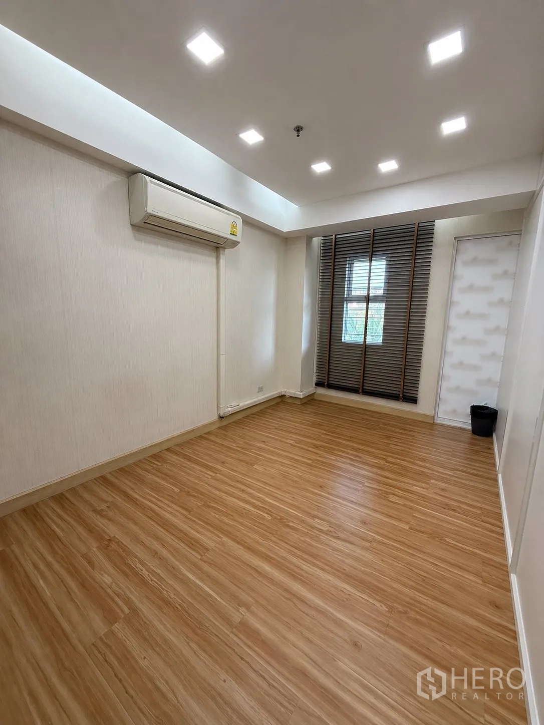 Home Office for rent or sale in Yan Nawa, Bangkok - Empty room with wood floors, recessed lights, air conditioner, and a window.