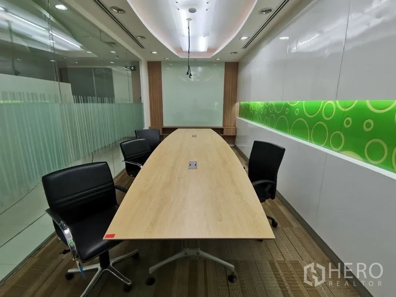 Office Space for rent in Bang Rak, Bangkok - Boardroom with oval table, black chairs and green backlit wall detail behind glass.