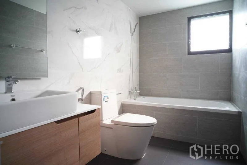 公寓 出租在Watthana, Bangkok - 现代浴室，浴缸、盥洗台与浅灰色墙砖。