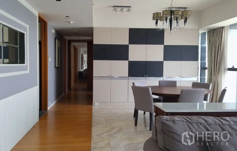 Condominium for rent in Sathon, Bangkok - Dining area with round table, chandelier, and full-height built-in cabinetry beside the hallway.