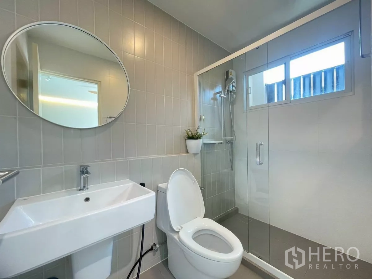 联排别墅 出租在Prawet, Bangkok - 现代浴室，椭圆镜与玻璃淋浴隔间。