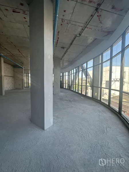 零售空间 出租在Phra Khanong, Bangkok - 弧形落地玻璃幕墙的商铺，室内未装修，可观街景。