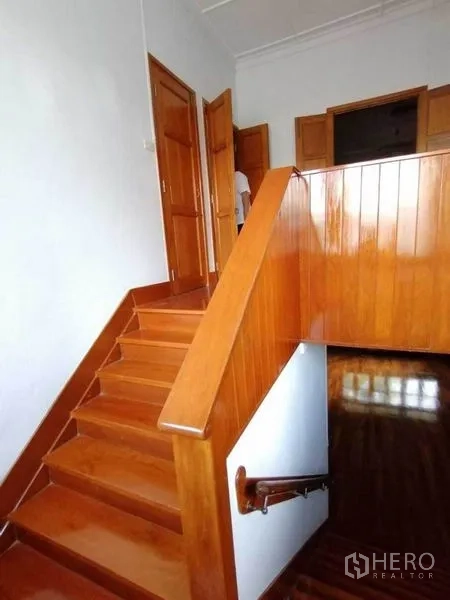Detached House for rent in Pathum Wan, Bangkok - Wooden staircase with handrail leading to the upper floor and interior doors.