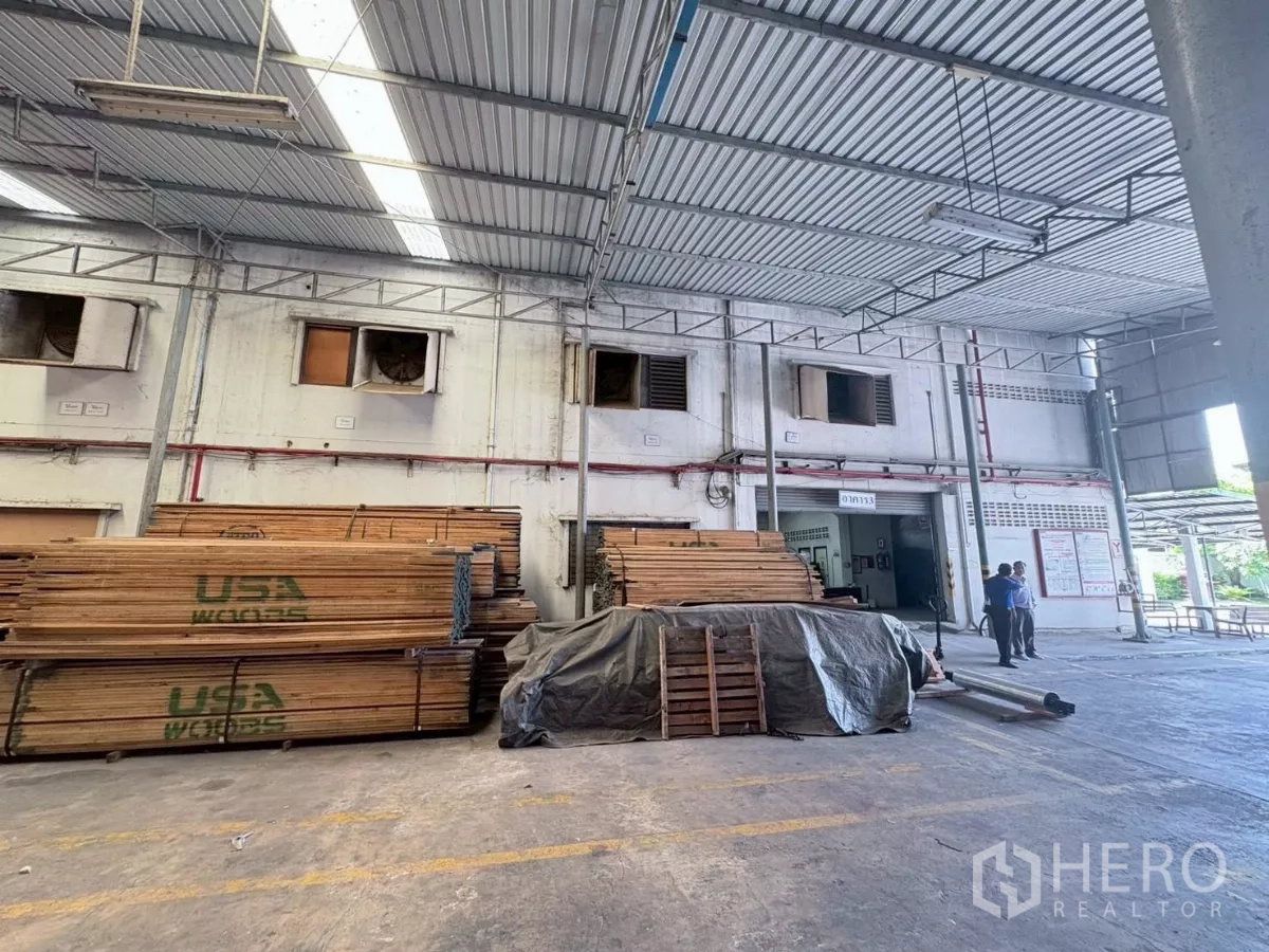 工厂 出租或出售在Bang Khun Thian, Bangkok - 有顶装卸区堆放木材，临近厂房外立面。