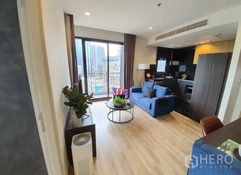 Condominium for rent in Chatuchak, Bangkok - Living area with blue sofa, round coffee table and sliding door to the balcony.