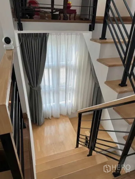 Detached House for rent in Bueng Kum, Bangkok - Staircase with wooden treads, black railings and a tall window with curtains.