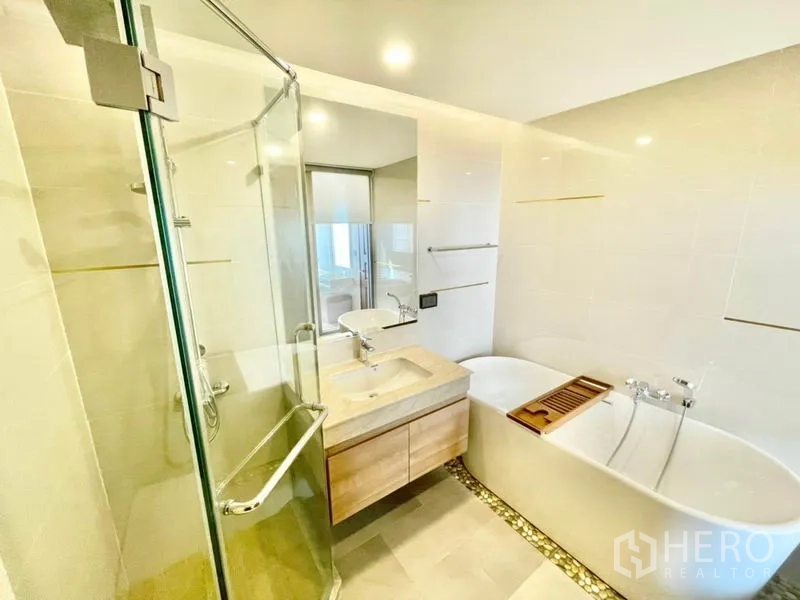 Condominium for sale in Huai Khwang, Bangkok - Bathroom with glass shower, bathtub and single vanity.