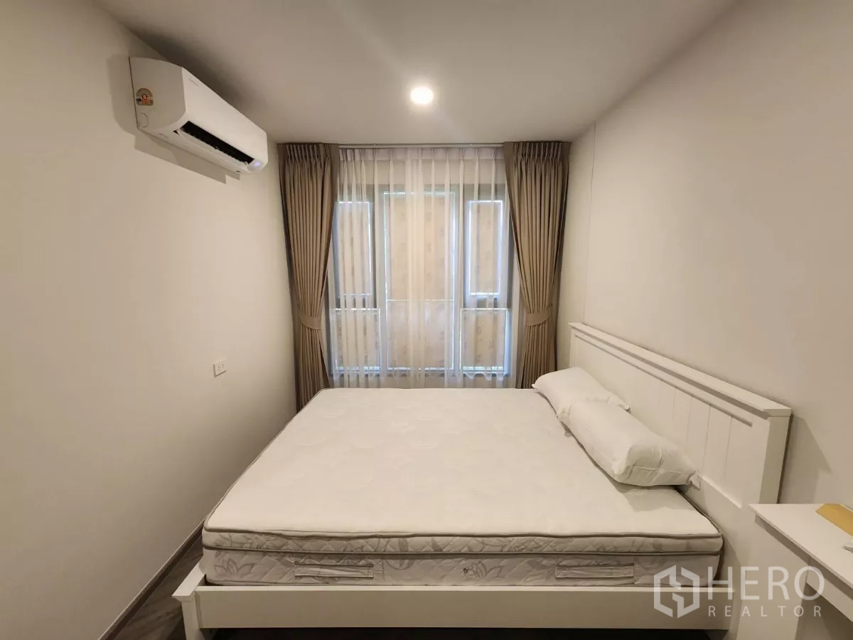 Townhouse for rent in Khlong Toei, Bangkok - Primary bedroom with queen bed, air conditioner and sheer curtains.