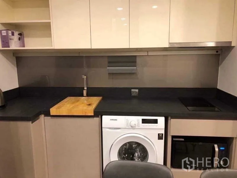 คอนโด ให้เช่าในKhlong Toei, Bangkok - มุมครัวทันสมัย เคาน์เตอร์สีเข้ม เตาไฟฟ้า อ่างล้างจาน ตู้ลอย และเครื่องซักผ้าแบบฝาหน้า