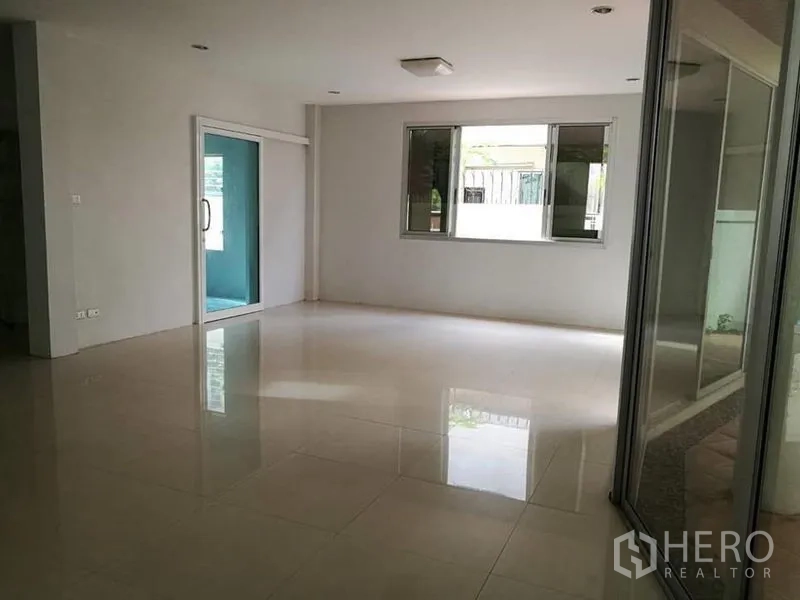 独立式住宅 出租在Phra Khanong, Bangkok - 采光充足的客厅，带大窗与通往日光房的推拉玻璃门。