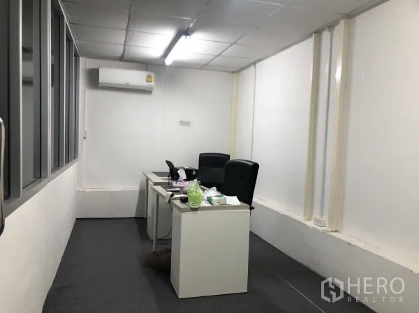 Warehouse for rent in Wang Thonglang, Bangkok - Narrow office workspace with two desks, chairs, and air conditioner.
