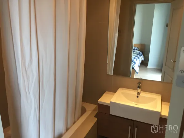 คอนโด ให้เช่าในBangkok - ห้องน้ำสมัยใหม่ พร้อมอ่างล้างหน้า กระจกบานใหญ่ และอ่างอาบน้ำพร้อมม่าน