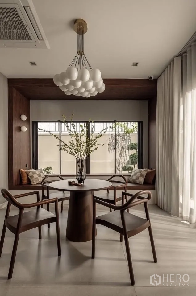 Detached House for rent or sale in Lat Krabang, Bangkok - Cozy dining nook with round table, four chairs, window bench seating, and chandelier.