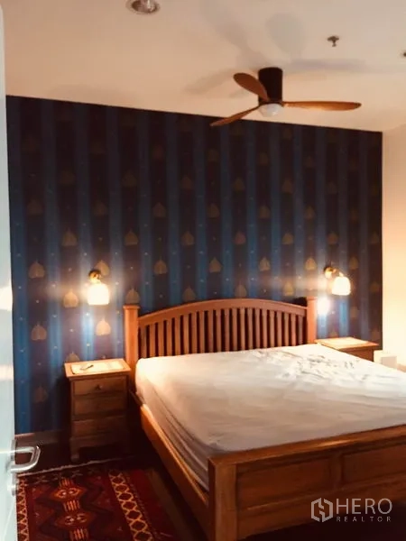 คอนโด ให้เช่าในBang Kapi, Bangkok - ห้องนอนเตียงไม้ ผนังสีฟ้าเข้ม โคมแขวนหัวเตียง และพัดลมเพดาน