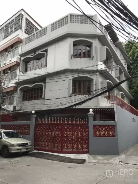 สำนักงานที่บ้าน ให้เช่าในDusit, Bangkok - มุมมองตัวตึกโฮมออฟฟิศ 3 ชั้น พร้อมหน้าต่างซุ้มโค้งและรั้วเหล็กลายไทยสีแดง