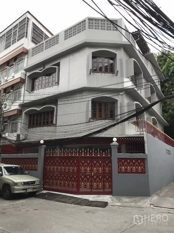Home Office for rent in Dusit, Bangkok - Corner view of a three-storey home office with arched windows and a decorative red gate.