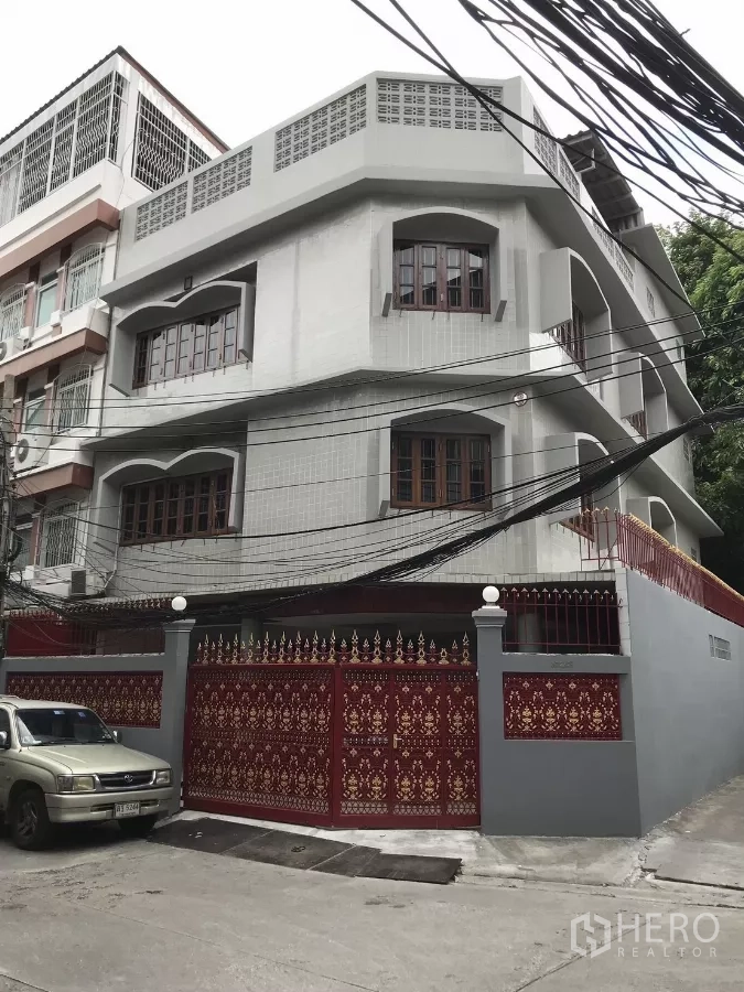 Home Office for rent in Dusit, Bangkok - Corner view of a three-storey home office with arched windows and a decorative red gate.