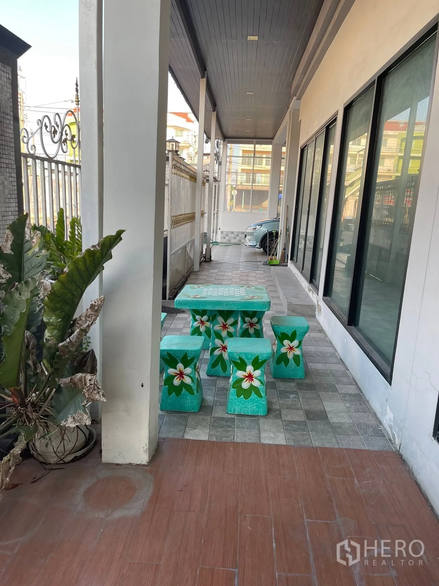 Detached House for rent or sale in Lam Luk Ka, Pathum Thani - Side covered patio with green outdoor table set and driveway parking.