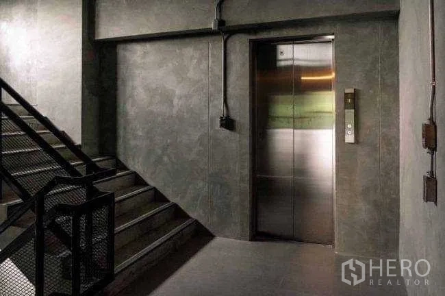 Office Space for rent or sale in Lak Si, Bangkok - Industrial stairwell with a stainless-steel elevator beside metal mesh stairs.