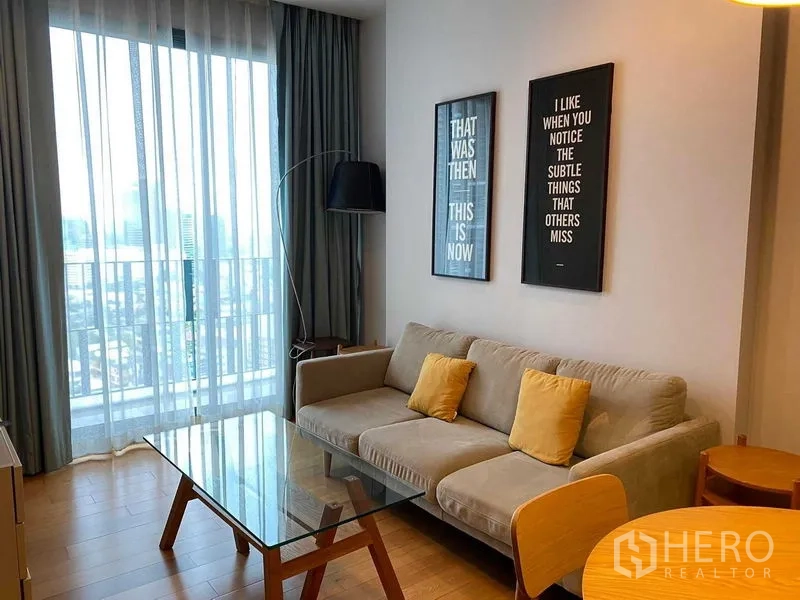 คอนโด ให้เช่าในKhlong Toei, Bangkok - ห้องนั่งเล่นมีโซฟาสีเทา โต๊ะกลางกระจก และหน้าต่างสูงจรดเพดานมองเห็นวิวเมือง