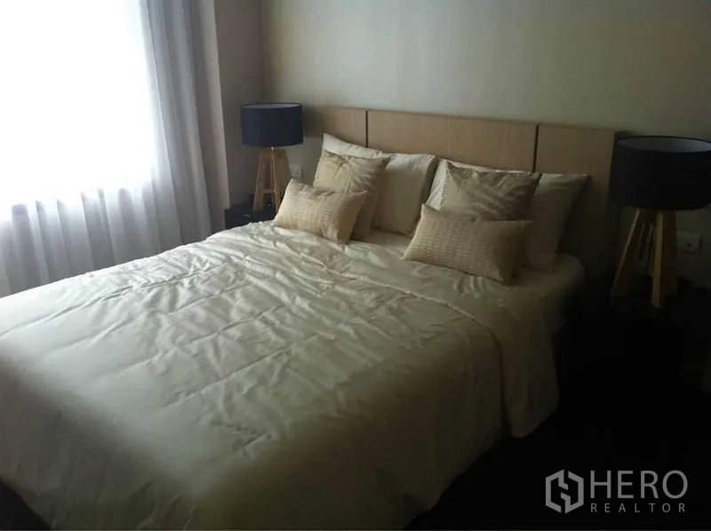 公寓 出售在Ratchathewi, Bangkok - 温馨卧室，米色床品，两盏三脚床头灯，窗边纱帘采光。