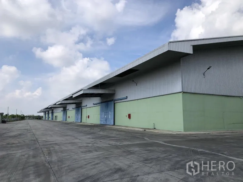 Warehouse for rent in Phra Nakhon Si Ayutthaya - Long facade of warehouses featuring multiple loading bays, canopies and fire hose cabinets.