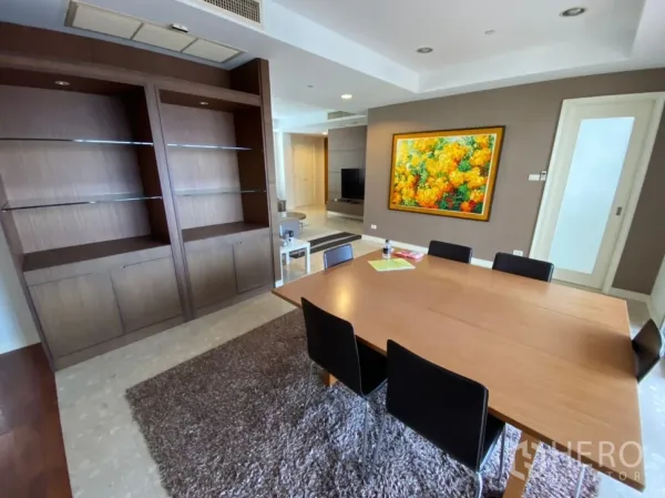 Condominium for rent in Watthana, Bangkok - Dining room with wooden table, built-in shelving and colorful wall art.