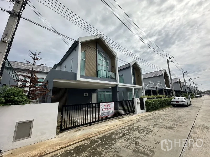 บ้าน ขายในLam Luk Ka, Pathum Thani - มุมมองด้านหน้า บ้านพร้อมรั้วเหล็กสีดำและที่จอดรถในร่ม