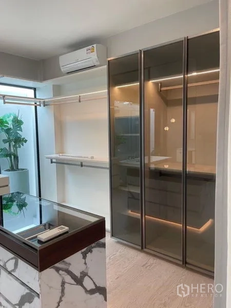 Detached House for rent or sale in Saphan Sung, Bangkok - Walk-in closet with glass-front wardrobes and a marble-topped island.