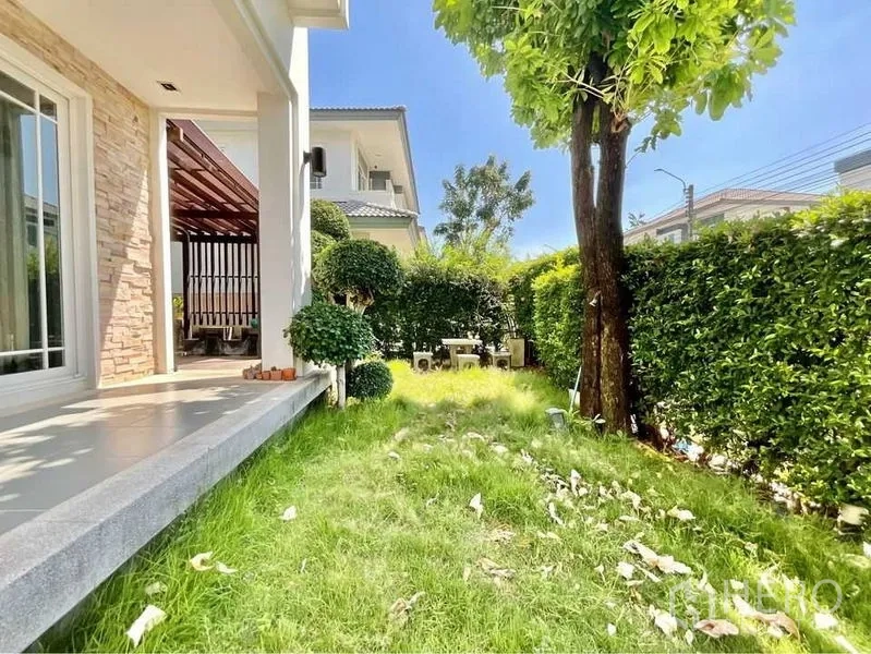Detached House for sale in Prawet, Bangkok - Private green garden with lawn, mature tree, hedges and a side patio beside the house.