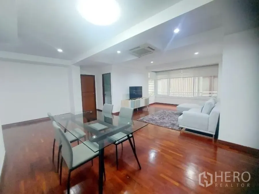 คอนโด ให้เช่าในWatthana, Bangkok - ห้องนั่งเล่นและรับประทานอาหารแบบเปิดโล่ง พร้อมโต๊ะกระจก โซฟาสีขาว ชั้นวางทีวี และพื้นไม้เงางาม