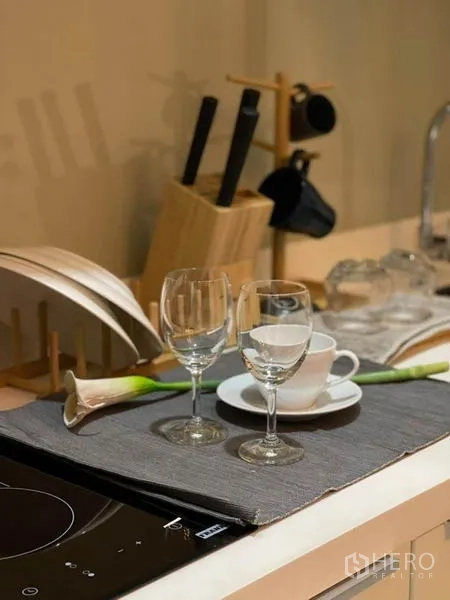 คอนโด ให้เช่าในRatchathewi, Bangkok - ภาพระยะใกล้ของเคาน์เตอร์ครัวขนาดกะทัดรัด เตาไฟฟ้าแก้ว และอุปกรณ์บนโต๊ะ